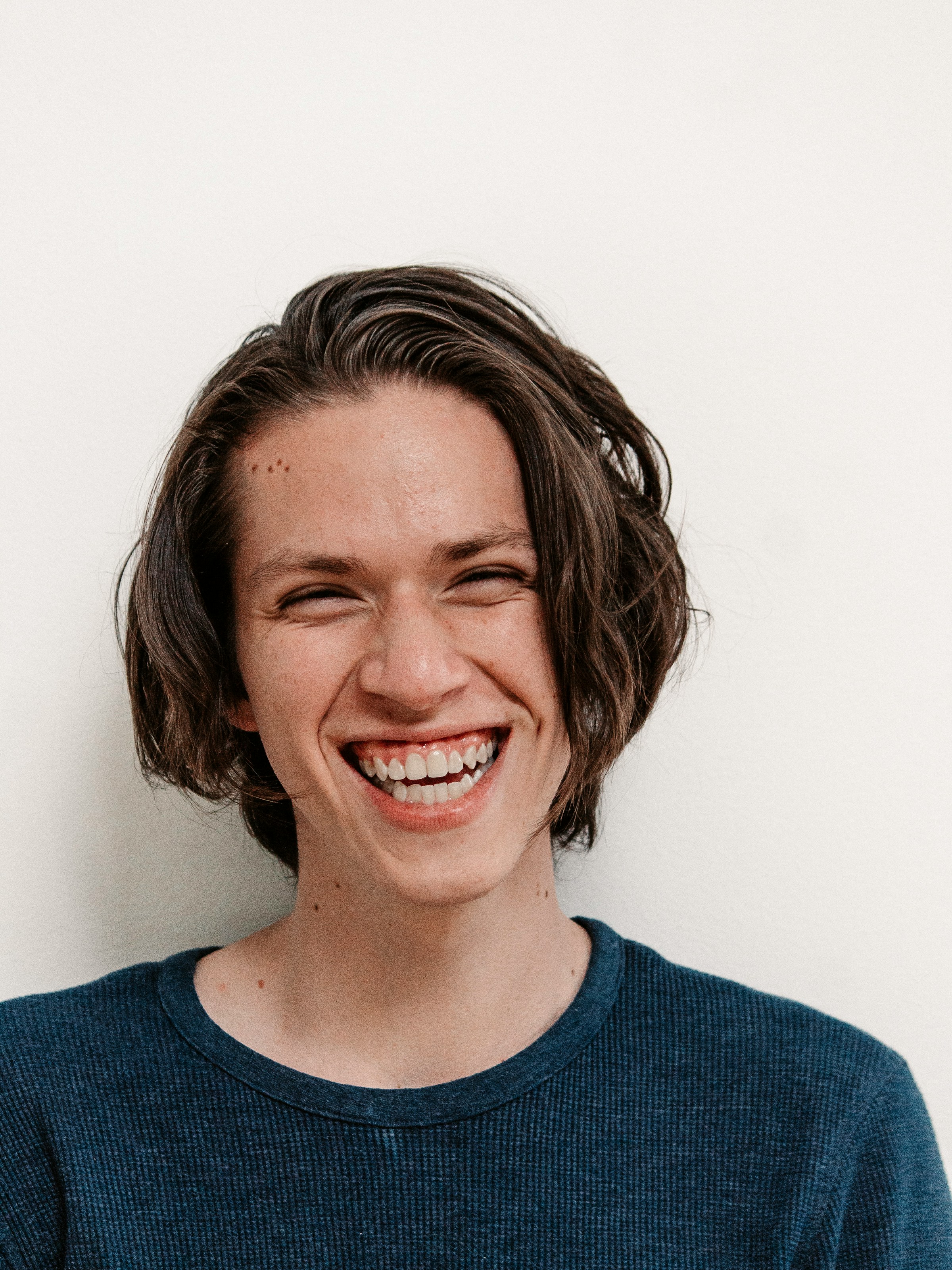 A young person with a wide, joyful smile against a soft white background